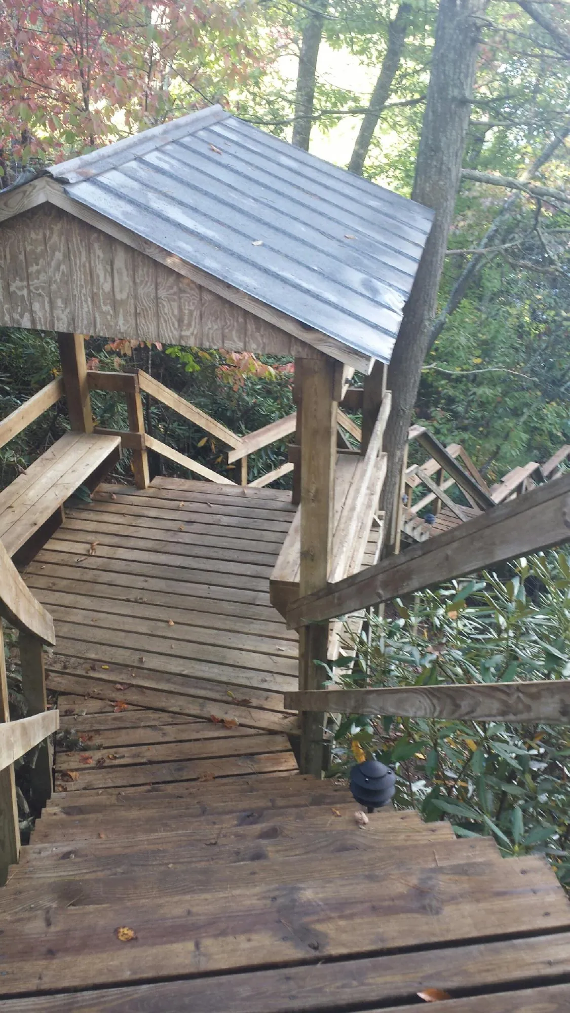 Metal roofed shelter over wooden steps on a wooded walkway — Skylight Repair & Installation work by our crew in Ludlow